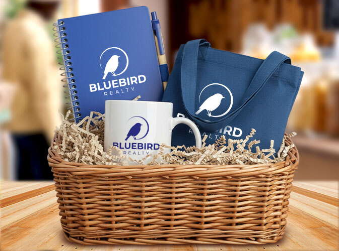 Gift box containing branded merchandise for Bluebird Reality, including a custom branded journal and pen set, a white coffee mug, and tote bag.